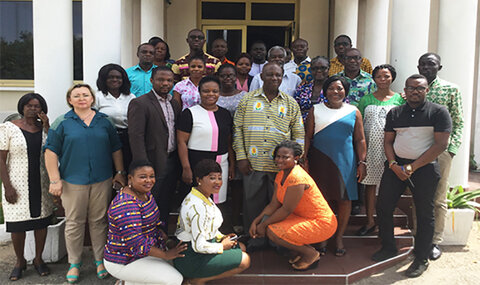 A group of African men and women standing smiling on steps outside a building